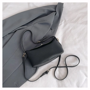 Close-up of black pebble grain leather texture on bucket bag with gold metal buckles