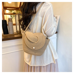 Detail of hand-woven straw bucket bag featuring pearl button closure and spiral pattern