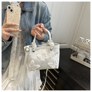 Detailed shot of white lace bucket bag with delicate 3D butterfly appliques and handles