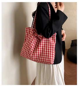 Detail of red checkered canvas tote bag with decorative side bow for daily casual use