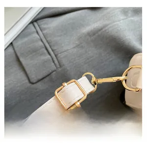 Detail of adjustable white leather strap with high-quality gold hardware on shoulder bag