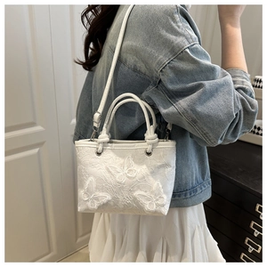 Detailed view of white lace bucket bag featuring 3D butterfly embroidery and floral lace