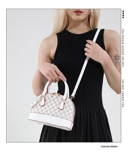 Detail of white leather monogram shell bag with gold hardware and red edge stitching