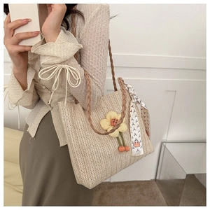 Détail d'un sac cabas en paille tressée avec fleur 3D et foulard en soie décoratif