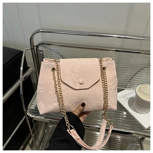 Detail of light pink snakeskin embossed texture and gold chain strap on the handbag