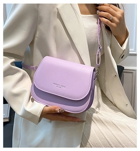 Close-up of light purple crossbody saddle bag with engraved fashion trend logo detail