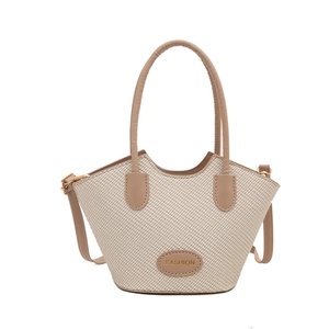 Oatmeal woven bucket bag with brown leather handles and adjustable shoulder strap
