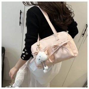 Detail of light pink tote bag featuring satin bows and a white cloud plush charm