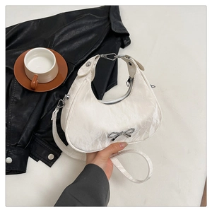 Détail d'un sac demi-lune blanc avec nœud argenté et cuir synthétique plissé