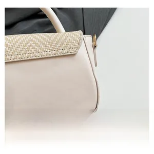 Close-up of cream textured faux leather and woven straw detail on a stylish handbag