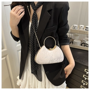 Detailed view of ivory embroidered floral handbag with golden ring handle on model