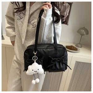 Close-up of black shoulder bag featuring pleated pockets and elegant bow decoration