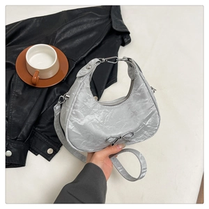 Détail du sac croissant argenté avec nœud métallique et texture plissée élégante