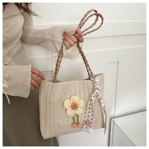 Détail du sac seau tissé beige avec charme floral jaune et foulard en soie à imprimé géométrique