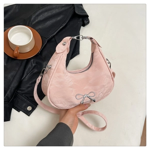 Detail of pink hobo bag with textured fabric, silver bow, and adjustable strap