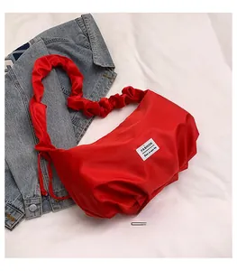 Detailed view of red pleated satin crescent bag with chic fashion label and ruched handle