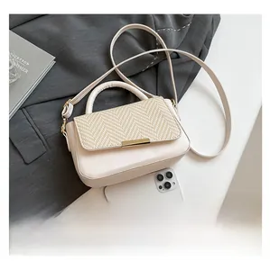 Chic beige leather shoulder bag with textured flap and gold buckle next to a phone