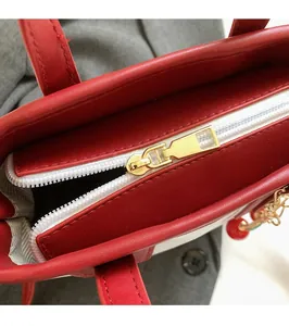 Detail of red leather bag showing smooth gold zipper and cherry pendant accessory