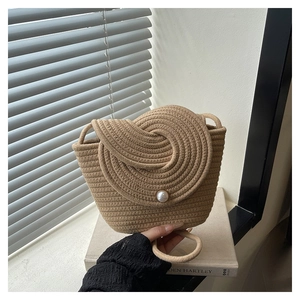Close-up of khaki woven straw bag with spiral flap and central pearl magnetic clasp