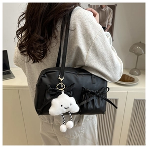 Detail of black ballet-style shoulder bag with ribbon bows and cute cloud plush pendant