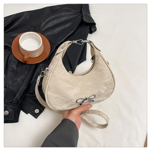 Detail of beige crescent bag featuring marble texture and silver bow metal buckle