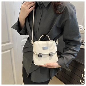 Detail of cream PU leather crossbody bag featuring silver buckles and adjustable strap