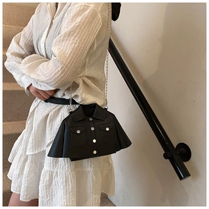 Unique jacket-shaped black crossbody bag with silver chain strap on a white dress