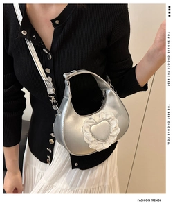 Detail showing metallic silver crescent bag with lace heart patch and adjustable strap