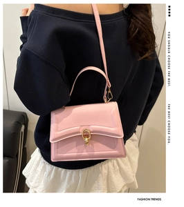 Detail of pink leather handbag showing stitching and gold ring buckle on model