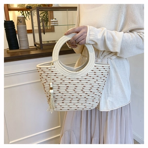 Detail of hand-woven beige tote bag with brown textures and wooden bead tassel