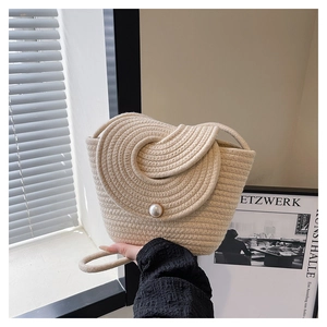Close-up of cream woven bucket bag with rope texture and white pearl button closure