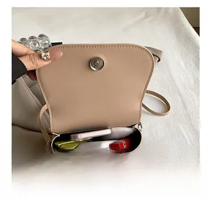 Detail view showing interior capacity of the beige faux leather saddle crossbody bag