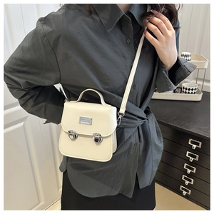 Détail du sac bandoulière crème avec boucles argentées et poignée dans un décor épuré