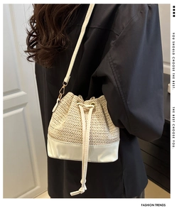 Detail of straw bucket bag with faux leather base and drawstring closure in beige