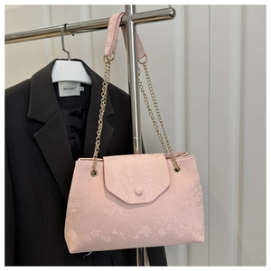 Detail of light pink snake pattern texture and gold chain on minimalist handbag