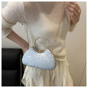 Detail of light blue floral embroidery on handbag with gold ring handle and chain strap