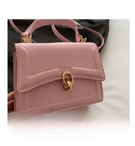 Detailed view of pink leather handbag with gold circular buckle and embossed lines