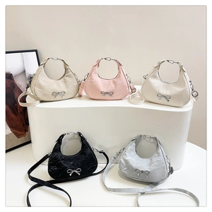 Detail of five crescent crossbody bags with metal bow accent and ring handles