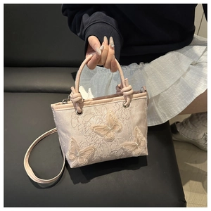 Detail of 3D lace butterfly embroidery on a pale pink crossbody bucket bag