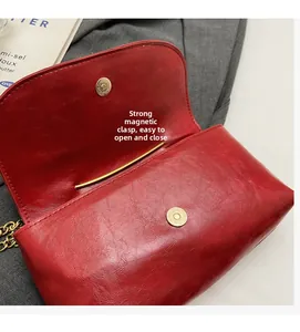 Detail of red crossbody bag with magnetic closure, vintage textured leather and gold chain