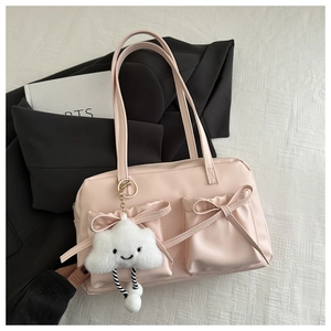 Pink shoulder bag with front pockets, bows, and a plush cloud charm on white fabric