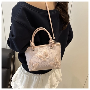 Detailed view of light pink lace bucket bag with 3D butterfly embroidery and crossbody strap
