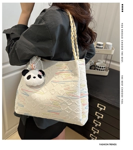 Detail of white tote bag with rainbow embroidery and cute panda plush keychain accessory