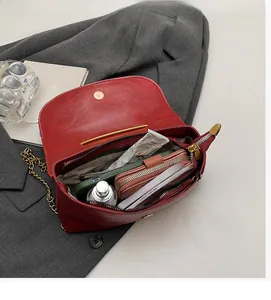 Spacious interior of dark red leather chain bag with items like phone and perfume