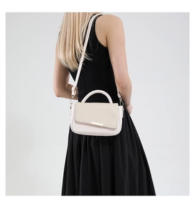 Détail d'un sac à bandoulière beige texturé tissé porté par un mannequin de dos