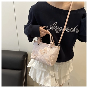 Detail of floral embroidery and 3D butterfly accents on a light pink satin bucket bag