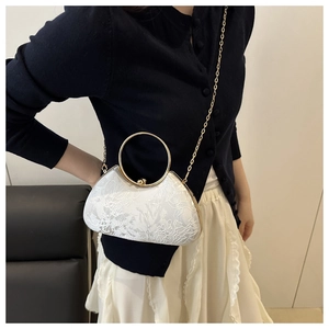 Detailed shot of white floral lace evening bag with gold round handle and chain strap