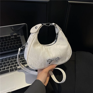Sac à bandoulière blanc en forme de croissant avec texture plissée et nœud métallique