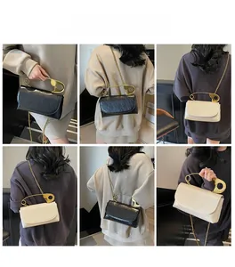 Detail of creative crossbody bag with large gold safety pin handle and chain strap