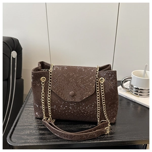 Détail d'un sac à main marron foncé effet serpent avec chaîne dorée élégante